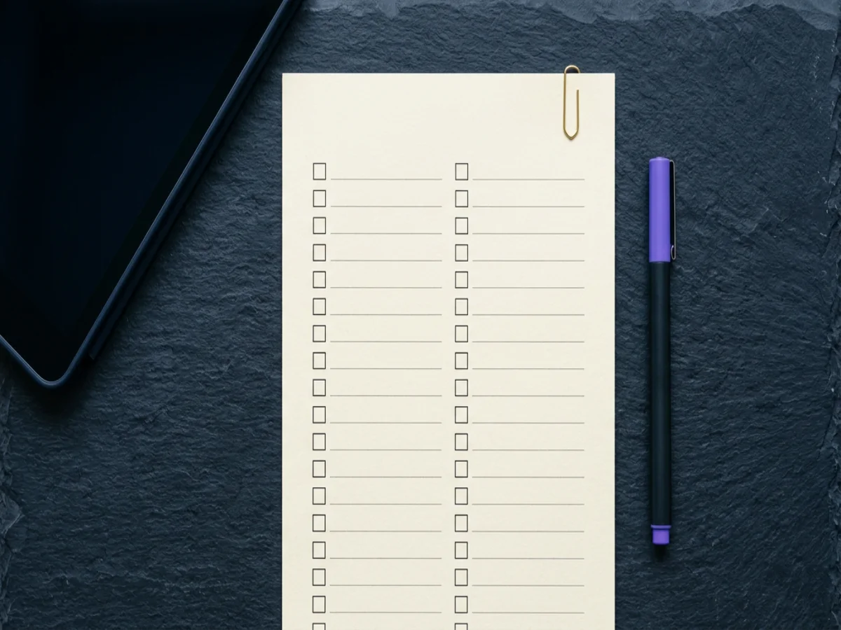 Checkliste und Stift auf dunklem Tisch, symbolisch für Qualitätssicherung, Bild 1200×900 px